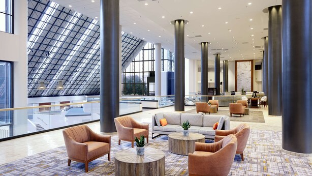 A spacious lobby with high ceilings, large windows, and modern furnishings including sofas and armchairs. - DoubleTree by Hilton Dallas Near the Galleria (Dallas)