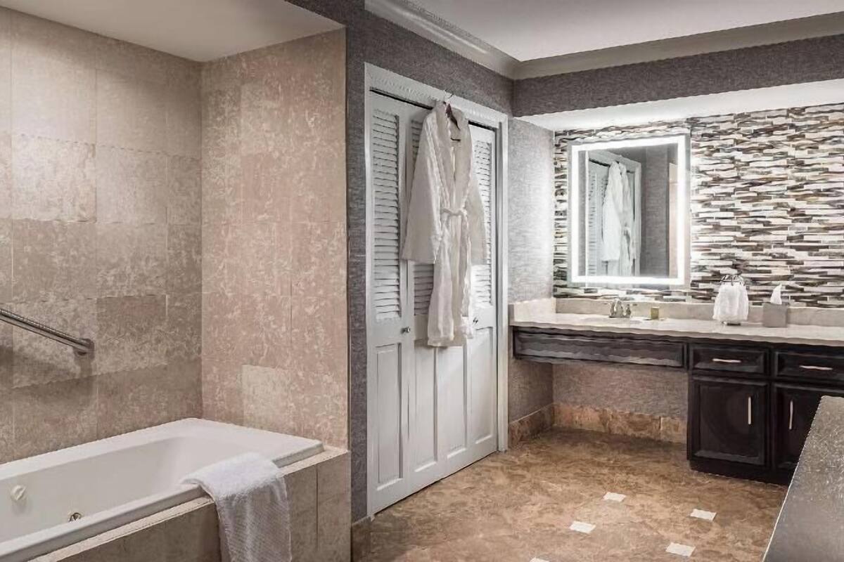 Ein modernes Badezimmer mit Badewanne, Duschbereich, Waschtisch mit Spiegel und Steinrückwand.