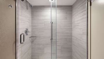 A glass-enclosed shower with a modern design, featuring a control panel and a handheld showerhead.