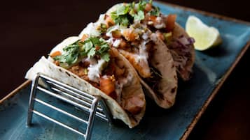 Três tacos em um prato azul com uma fatia de limão.