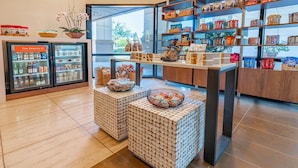 A store interior with shelves stocked with snacks, a refrigerated display case, and a checkout counter. - Sonesta San Jose - Milpitas (Milpitas)