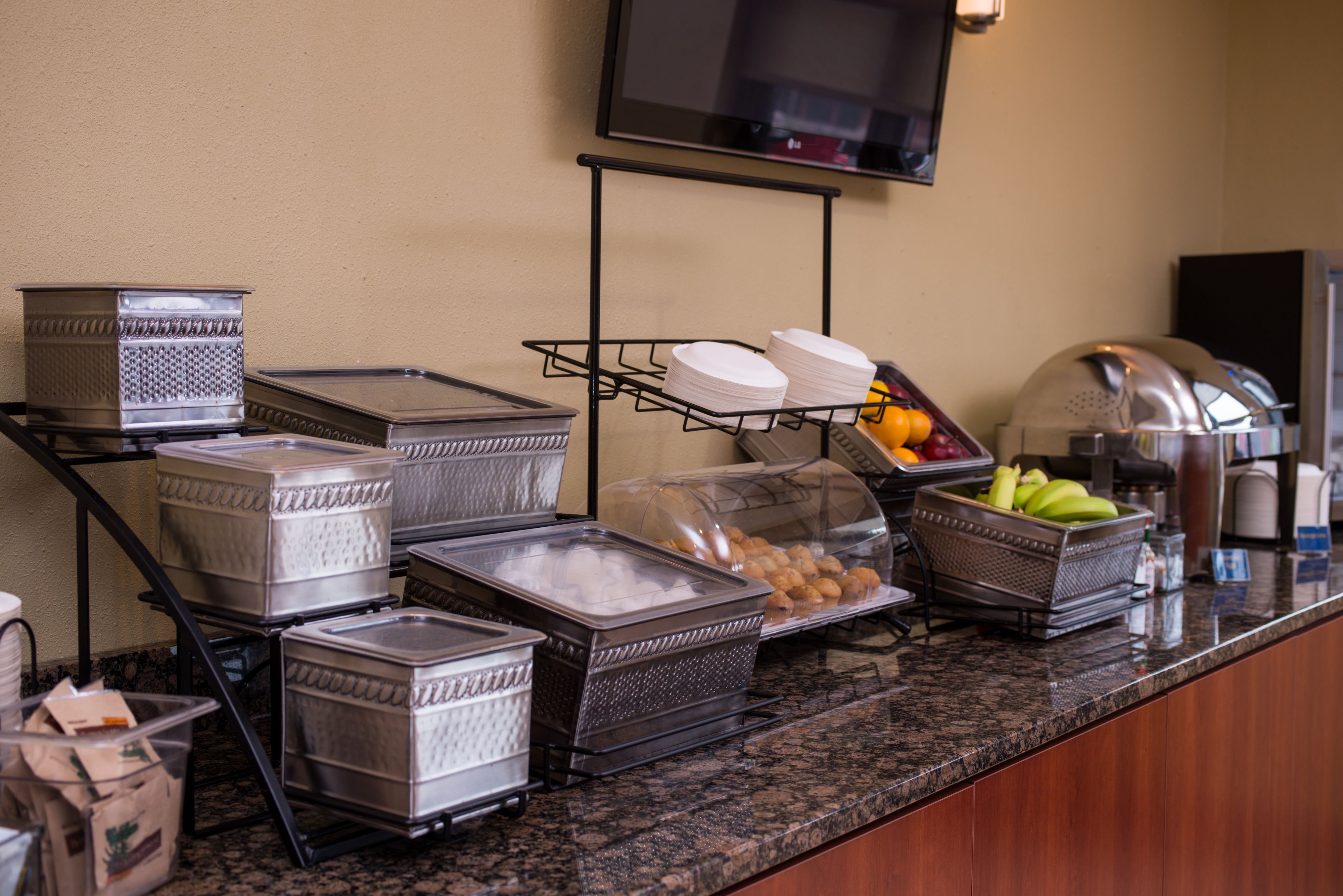 A buffet setup with various food containers and a fruit basket.