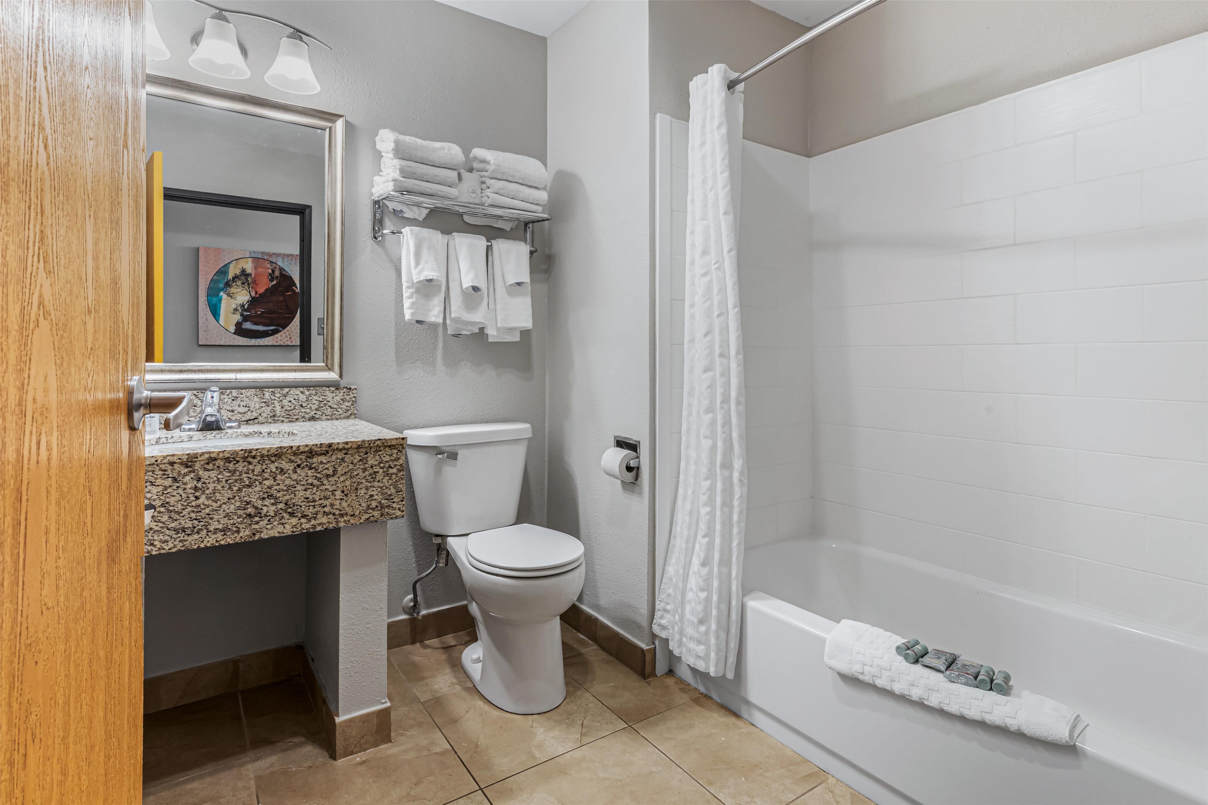 A bathroom with a toilet, sink, and bathtub. There are towels and toiletries on the wall.