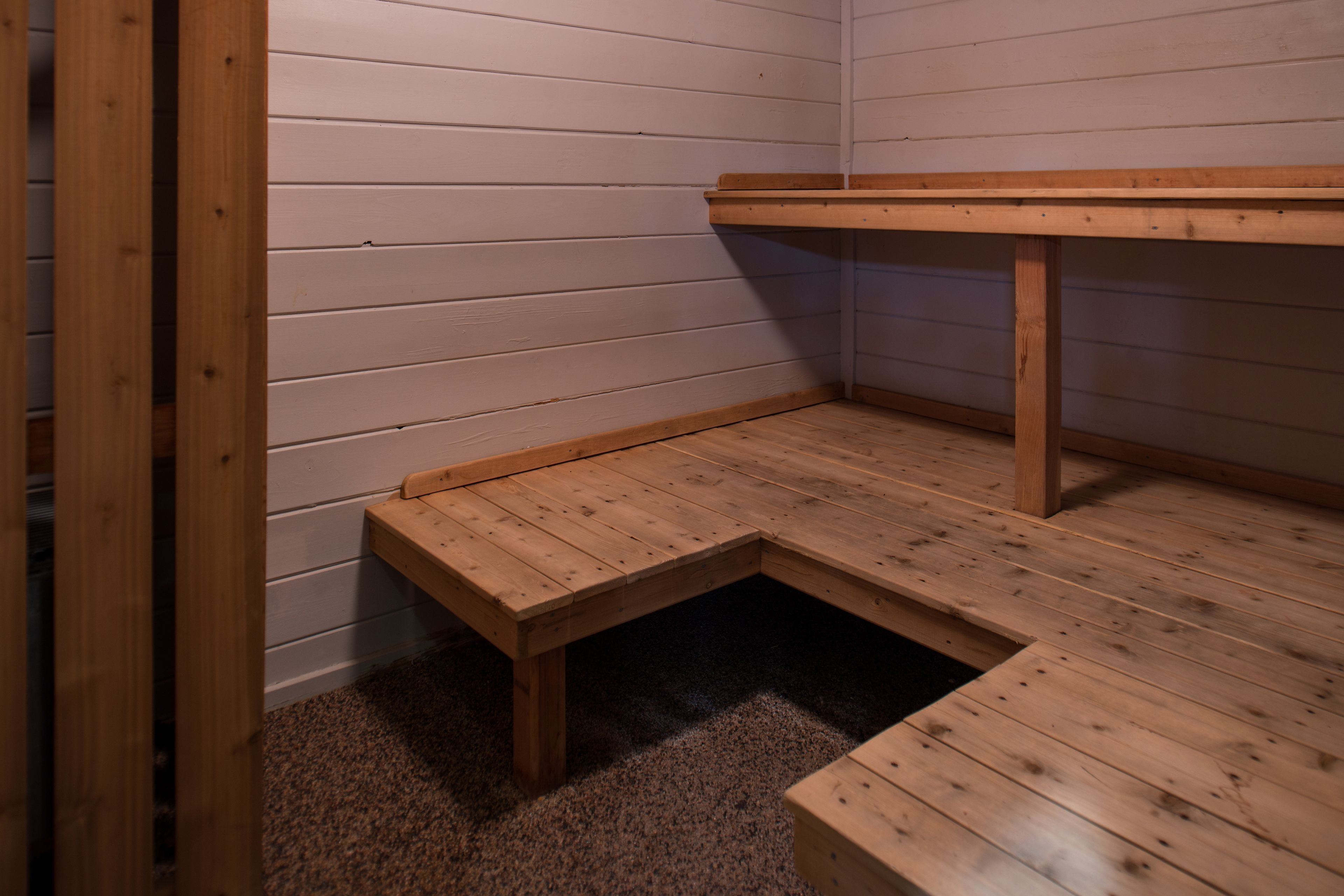 A corner of a room with wooden flooring and a bench.