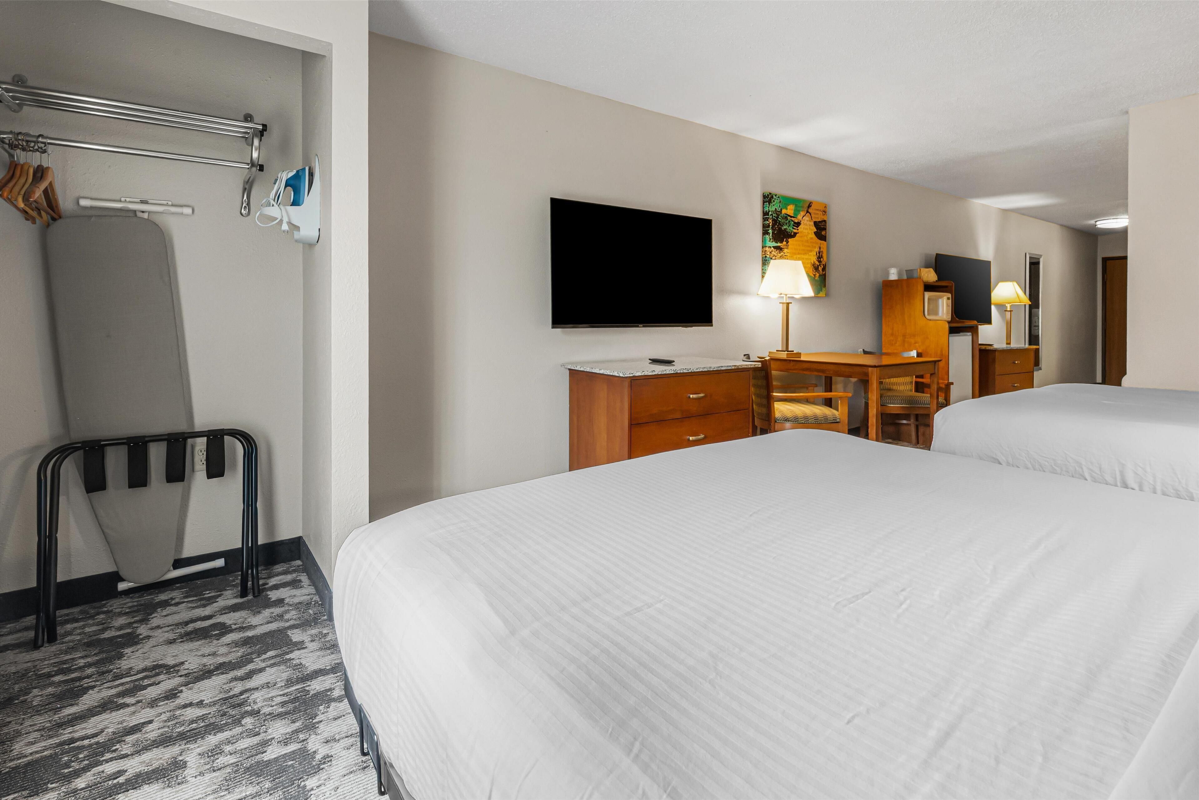 Une chambre d’hôtel avec deux lits, un bureau, une télévision et un espace douche.