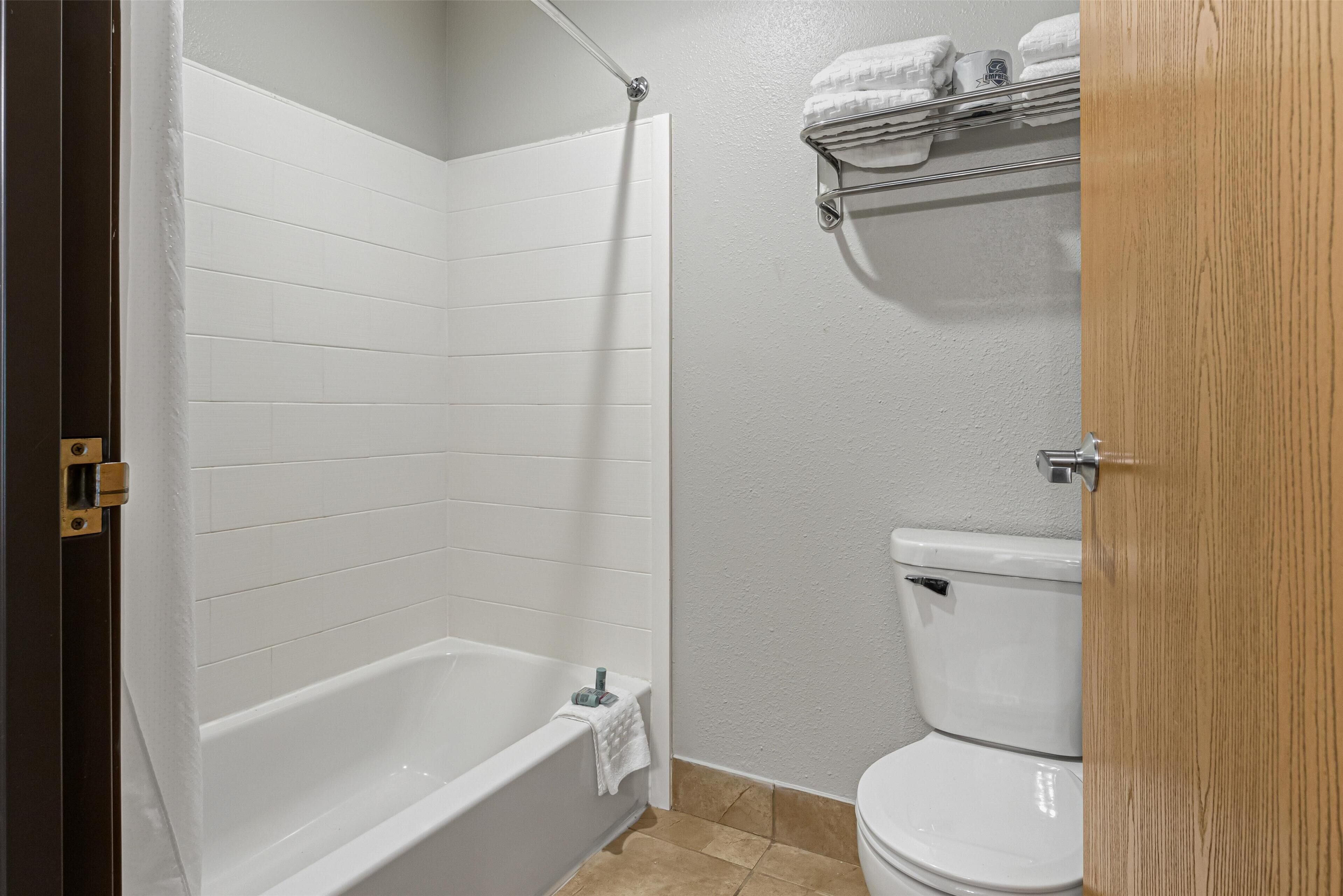 Une salle de bain avec une baignoire blanche, des toilettes blanches et un porte-serviettes avec des serviettes.