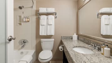 A bathroom with a bathtub, toilet, sink, and a large mirror.