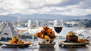 Una mesa con vistas a la ciudad, dos copas de vino y platos de comida.