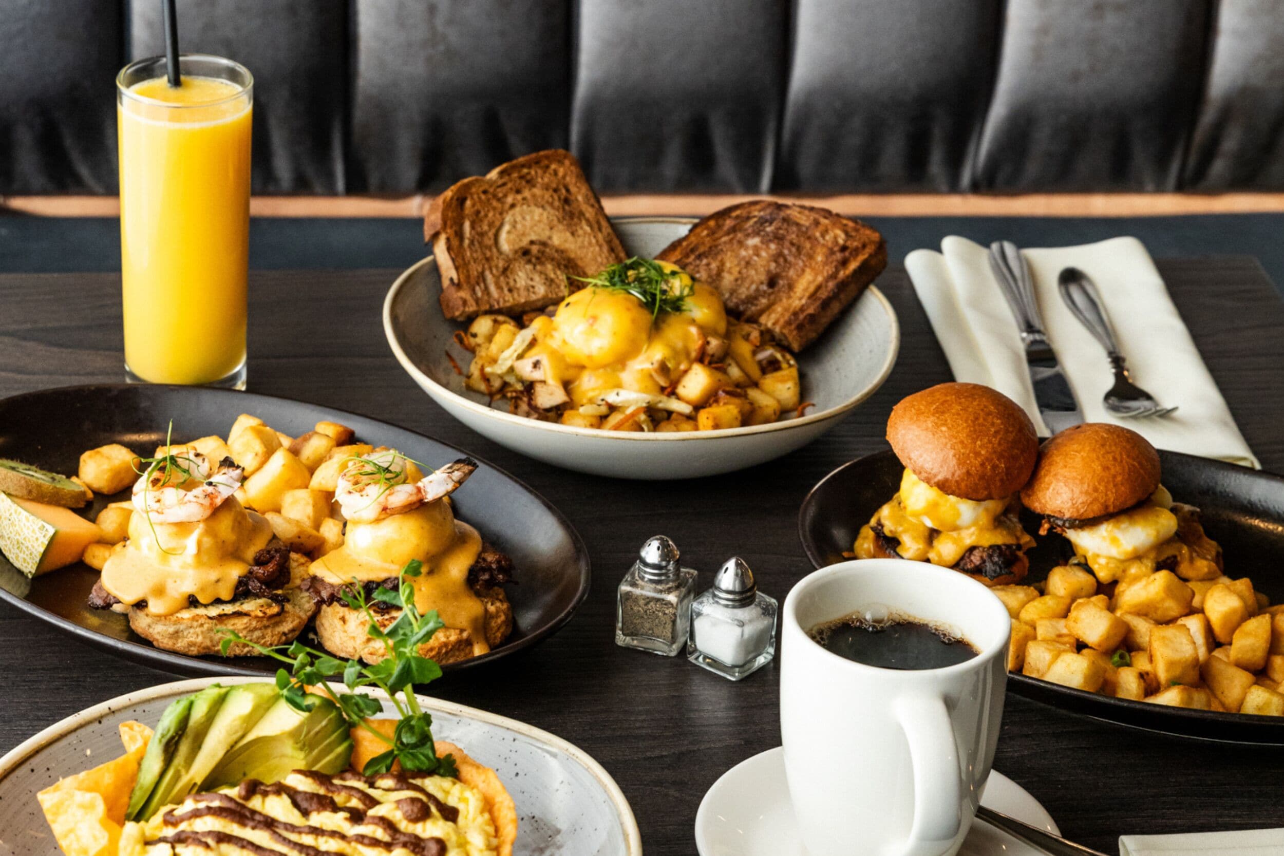 Une table mise pour le petit-déjeuner avec des toasts, des œufs, des pommes de terre et une tasse de café.