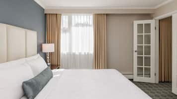 A hotel room with a large bed, a nightstand, a lamp, a window with curtains, and a door.