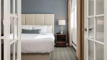 A hotel room with a bed, a nightstand, a lamp, and a view through an open door.