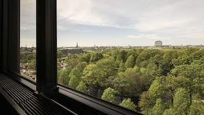 Vista desde una ventana que da a un paisaje urbano con un río, árboles y diversos edificios.