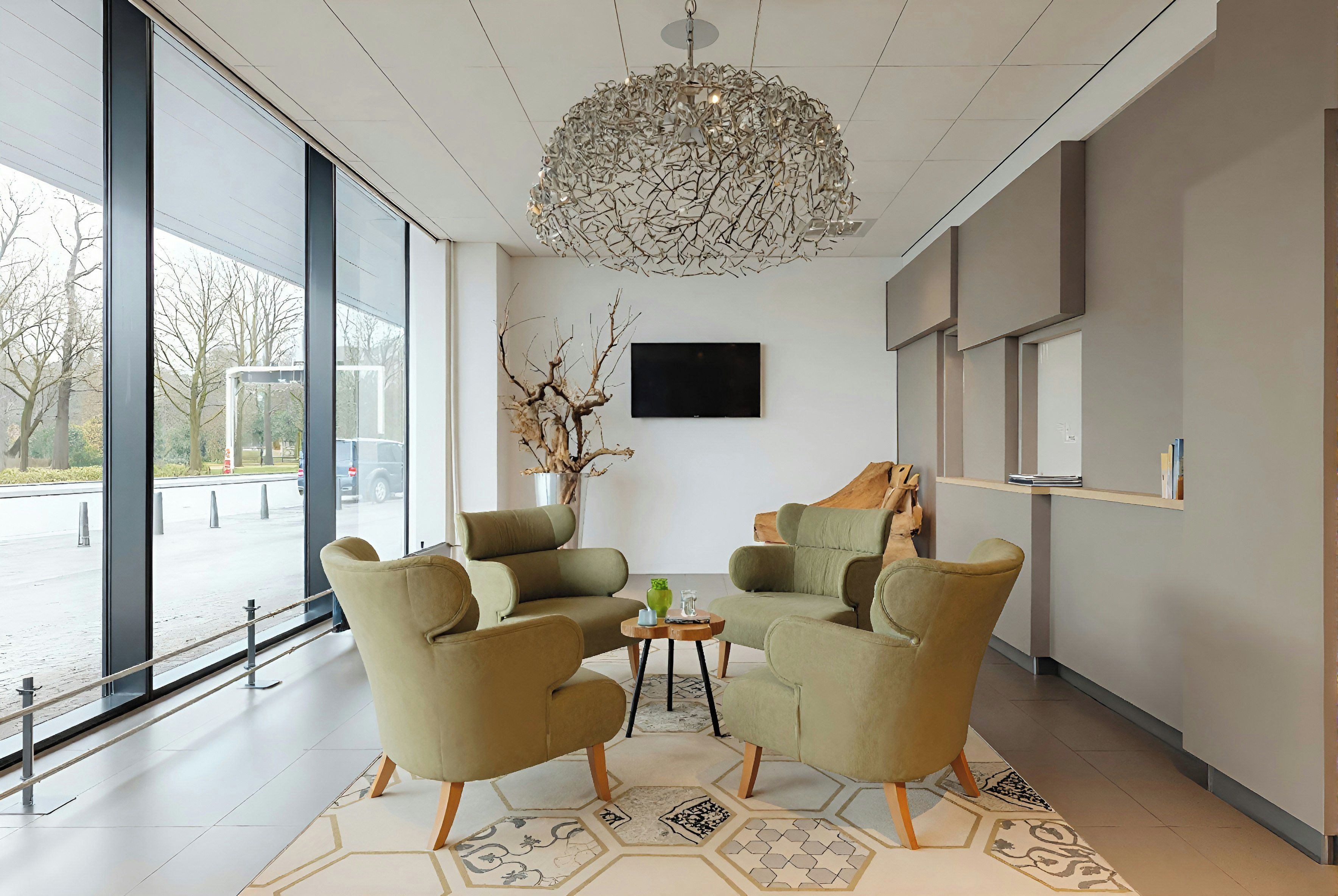 A modern interior with two armchairs, a small table, a decorative vase, and a large window offering a view of the outside.