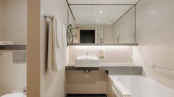 A modern bathroom with a sink, mirror, and bathtub.