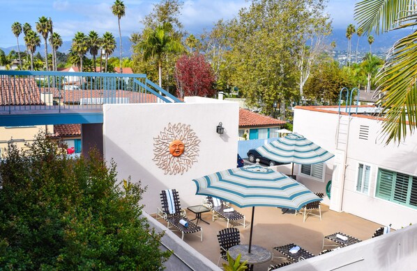 A rooftop patio with lounge chairs, umbrellas, and a decorative sun mural.