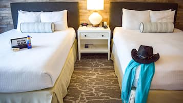 A hotel room with two beds, a nightstand with a lamp, a hat, and a scarf on one bed.
