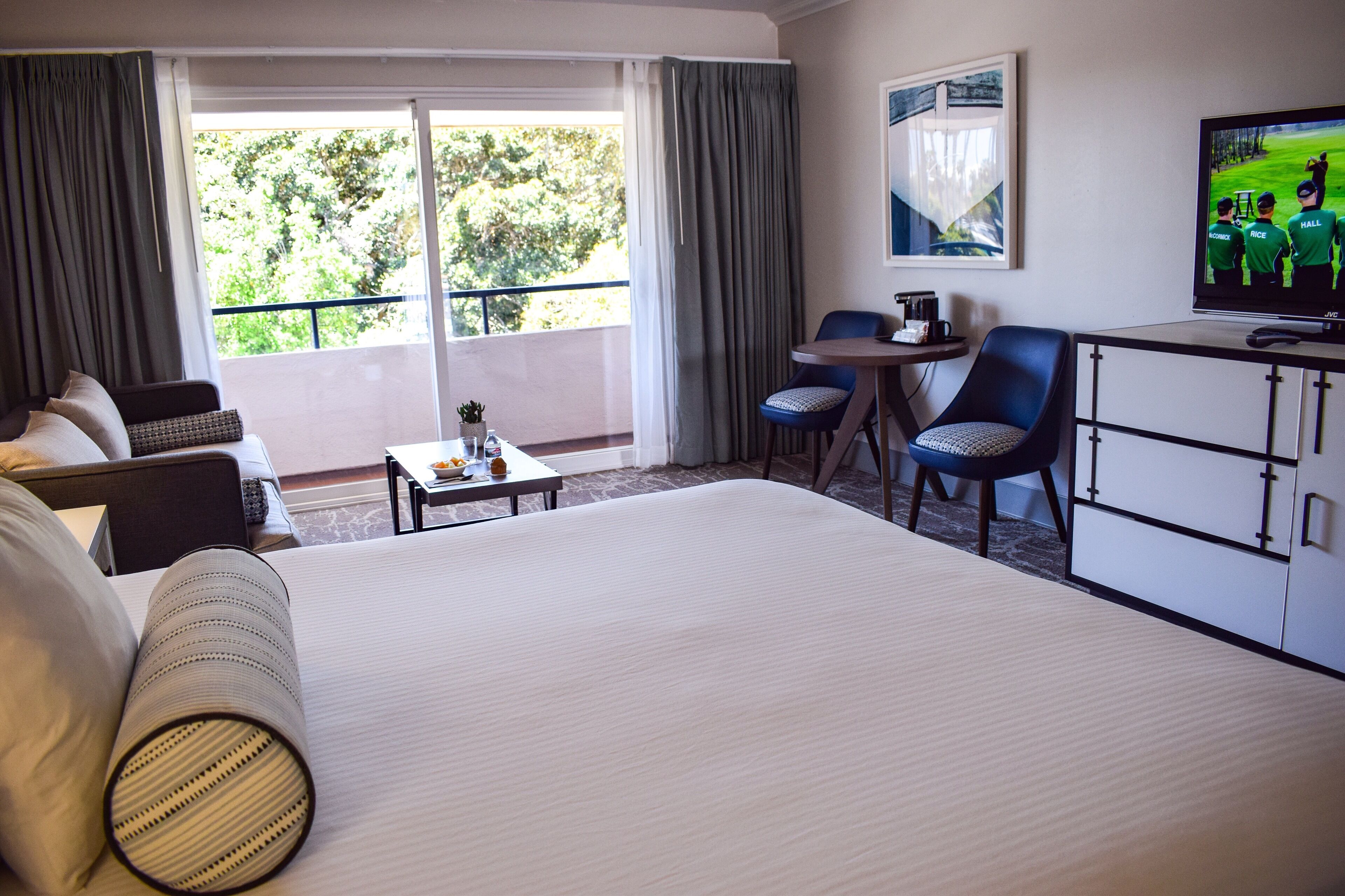 Une chambre d’hôtel avec un grand lit, un bureau, une chaise, une petite table et un téléviseur.