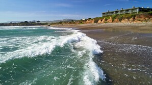 Un hôtel situé sur la côte, doté d’un long balcon offrant une vue sur la plage et l’océan.