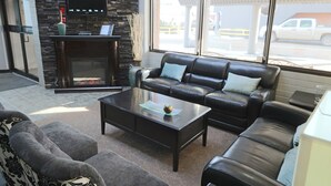 A modern living room with a fireplace, leather sofas, and a flat-screen TV. - Travelodge by Wyndham Grande Prairie (Grande Prairie)