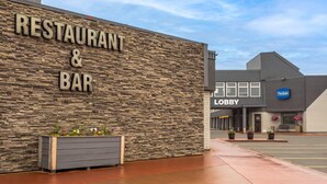 A restaurant and bar with a stone facade and a lobby entrance. - Travelodge by Wyndham Grande Prairie (Grande Prairie)