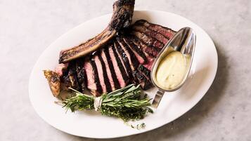 A plate of steak with a side of butter and herbs.