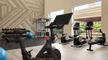 A gym with exercise equipment, a wall with a geometric pattern, and large windows.