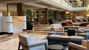 A spacious lobby with a high ceiling, modern furniture, and a chandelier. - DoubleTree by Hilton New York LaGuardia Airport (East Elmhurst)