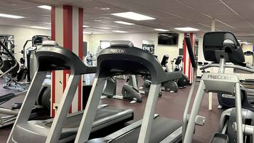 A gym with treadmills, weight machines, and a TV on the wall.