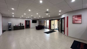 Un hall d’entrée spacieux comprenant un comptoir d’accueil, un distributeur automatique de billets et un espace détente.