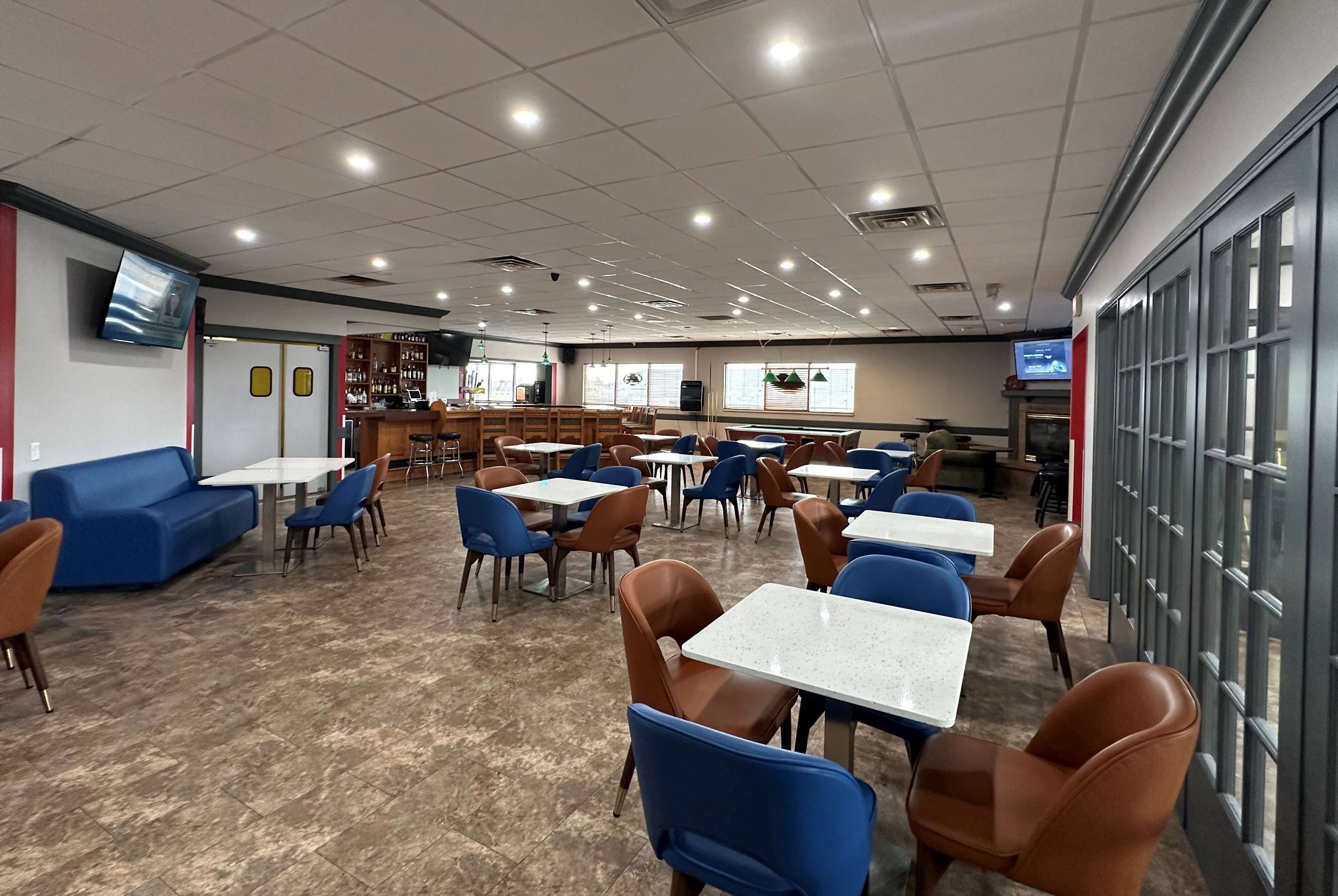 A spacious indoor dining area with multiple tables and chairs, a counter, and a television screen.