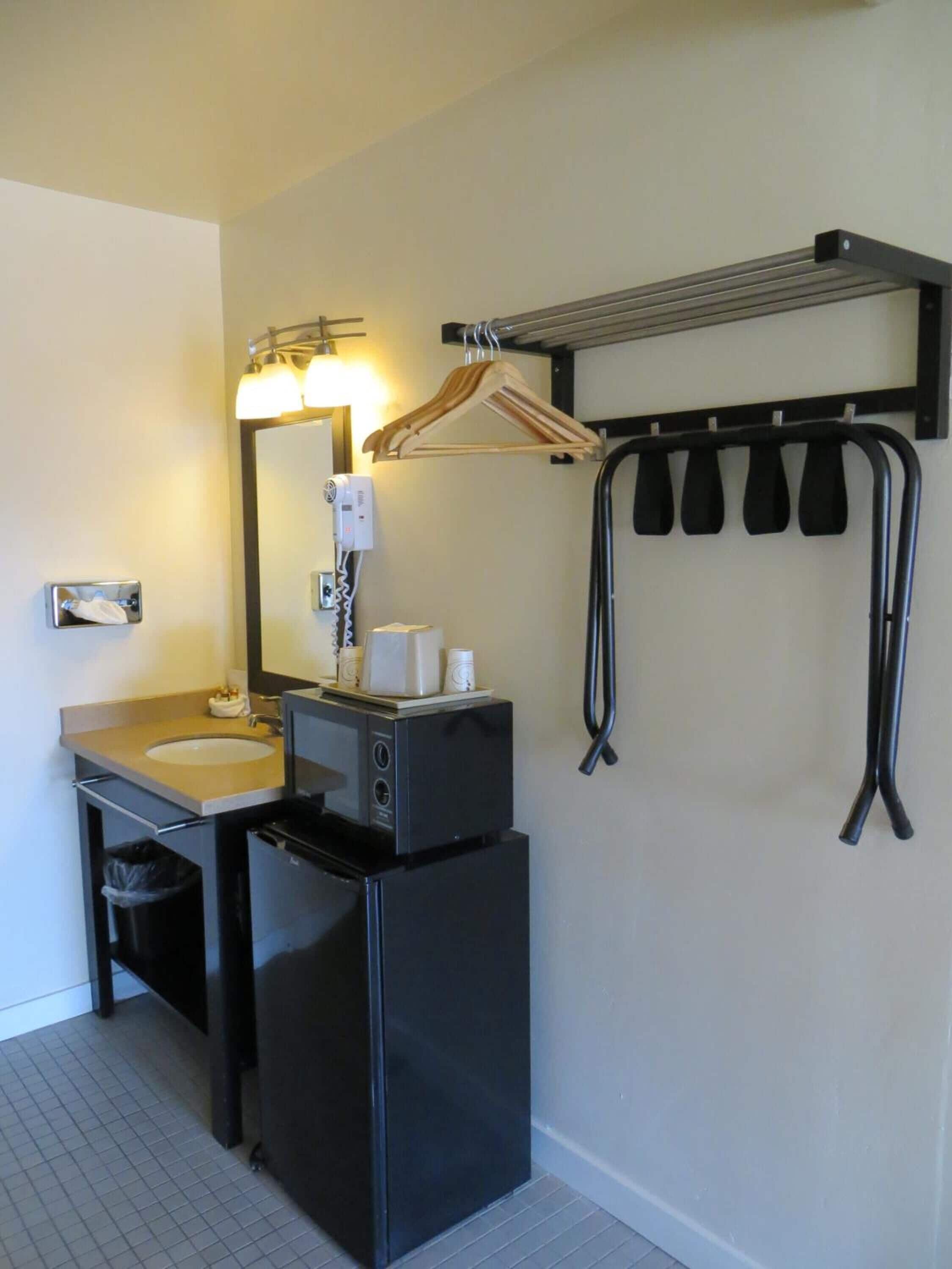 A compact bathroom with a sink, mirror, hairdryer, and a towel rack.