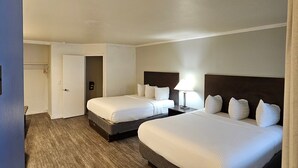 Ein Hotelzimmer mit zwei Betten, einem Kleiderschrank und einer Tür zum Badezimmer.