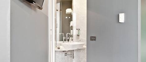 A modern bathroom with a large sink, mirror, and a shower area.