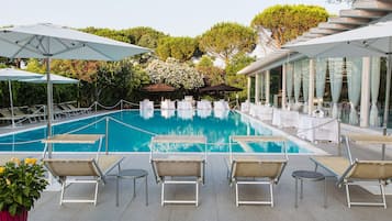 Relax by the serene pool surrounded by lush greenery and comfortable lounge chairs.