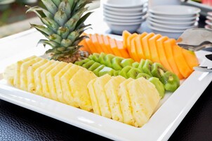 Un piatto bianco rettangolare con ordinate fette di ananas, kiwi e mango.