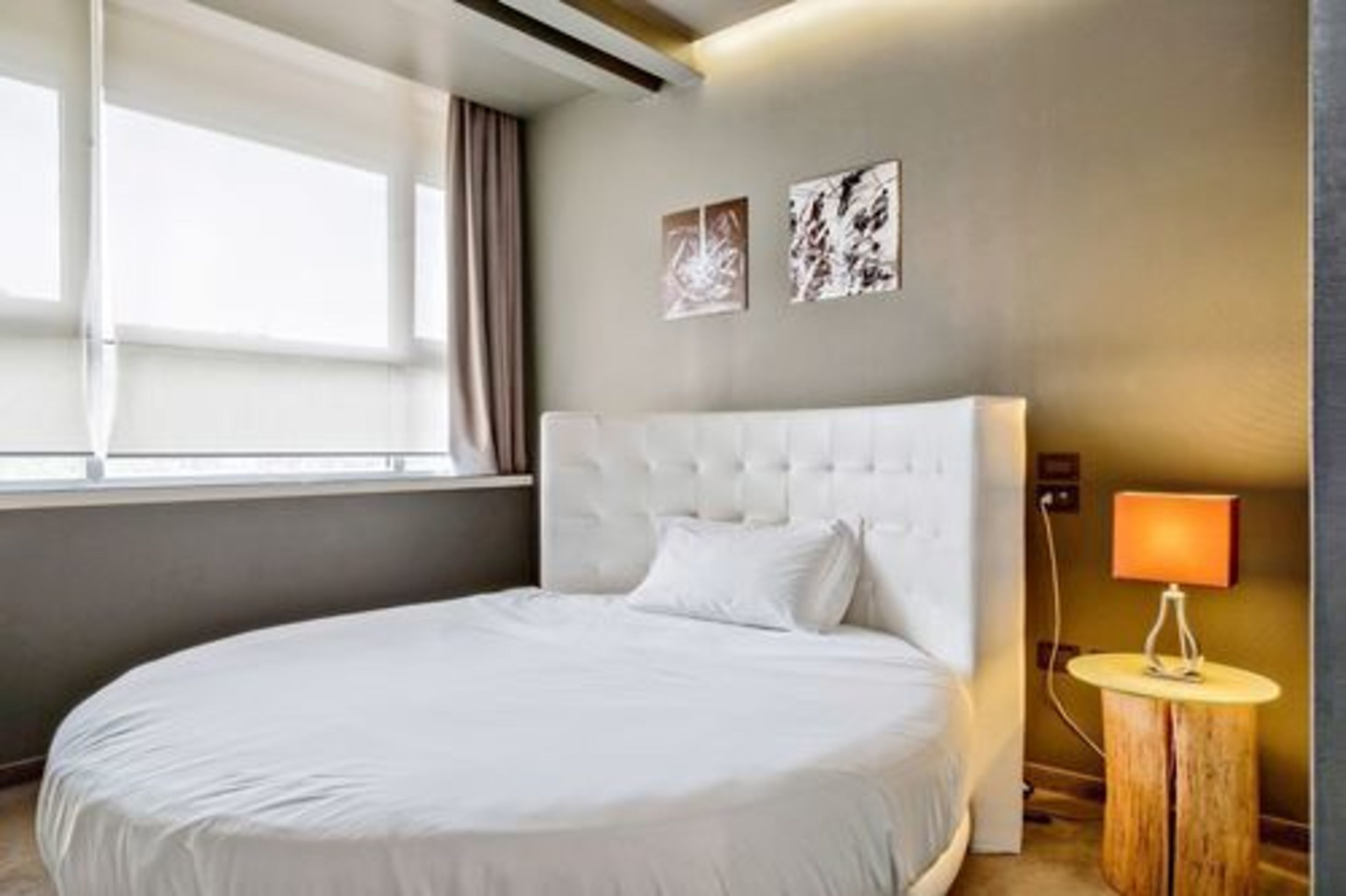 A hotel room with a large bed, a bedside lamp, and artwork on the wall.
