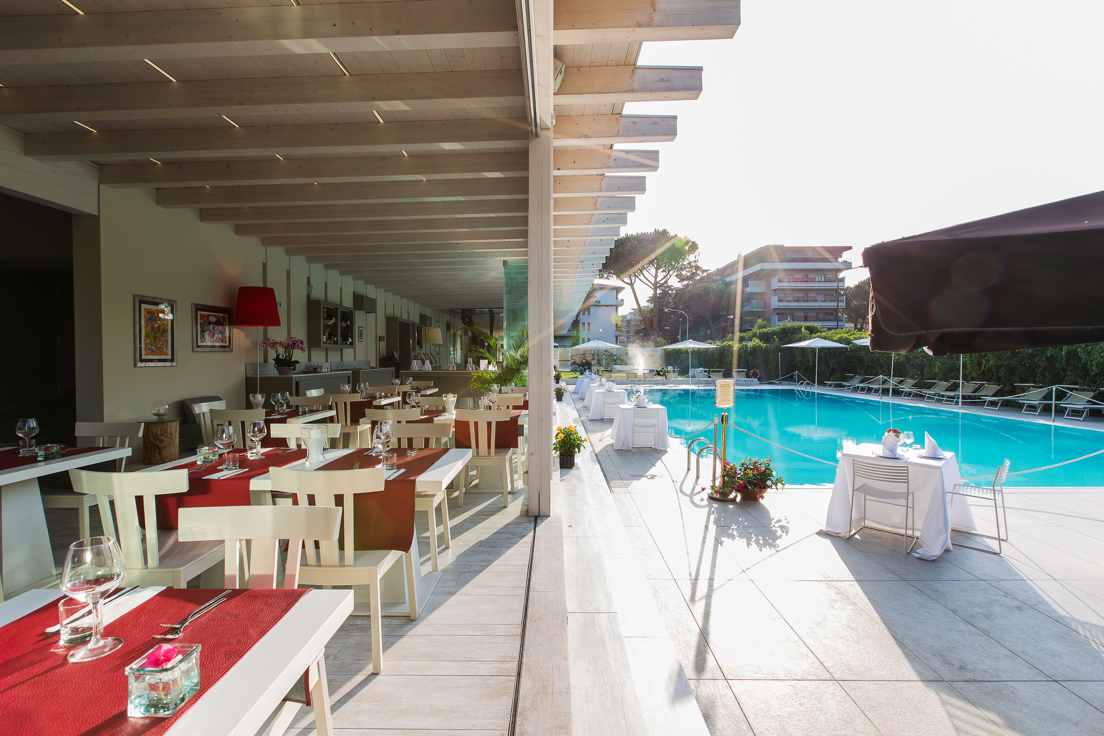 A poolside restaurant with outdoor seating, a pool, and a view of the cityscape.
