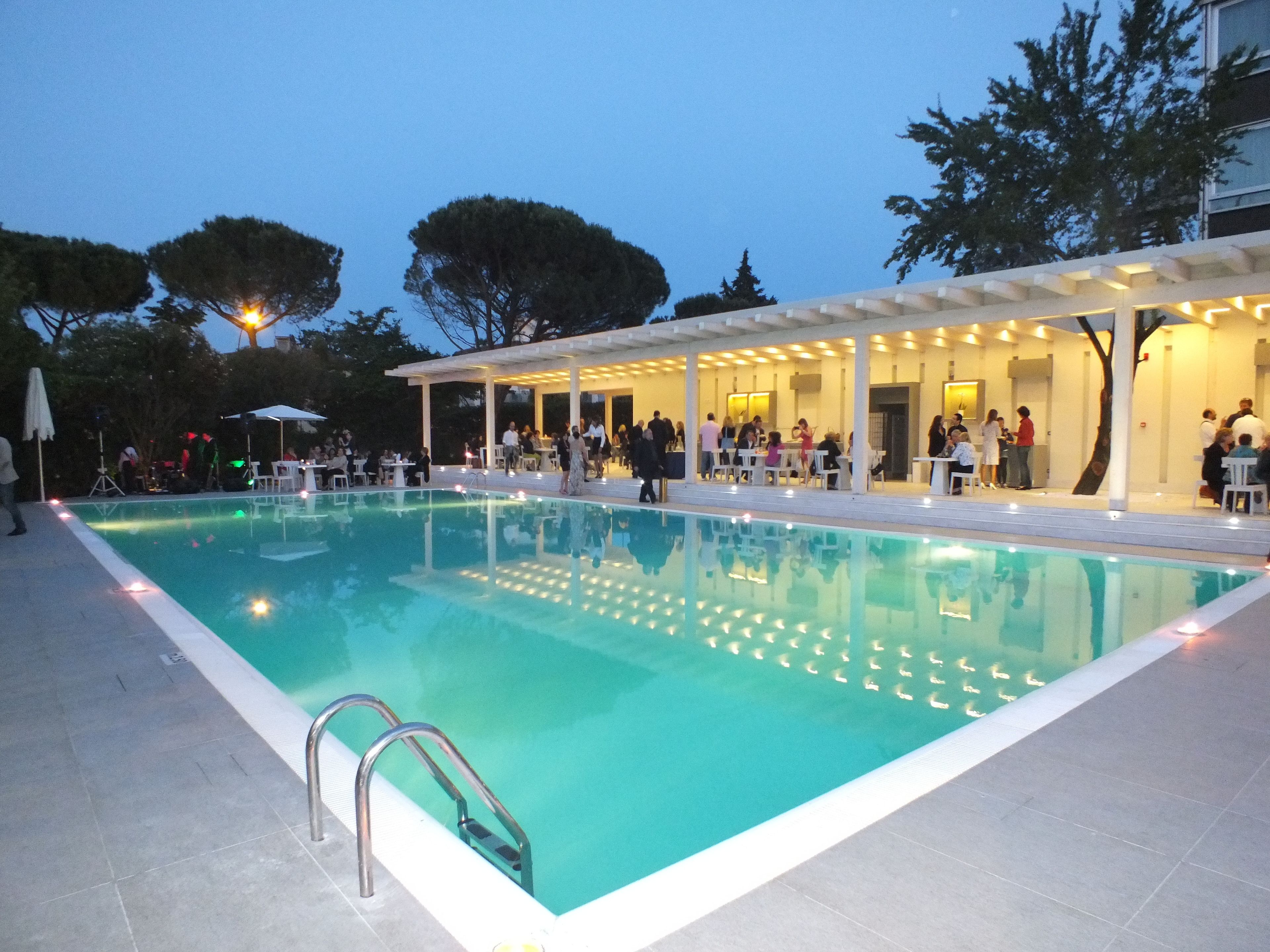 A swimming pool with a covered seating area and a tiled deck.