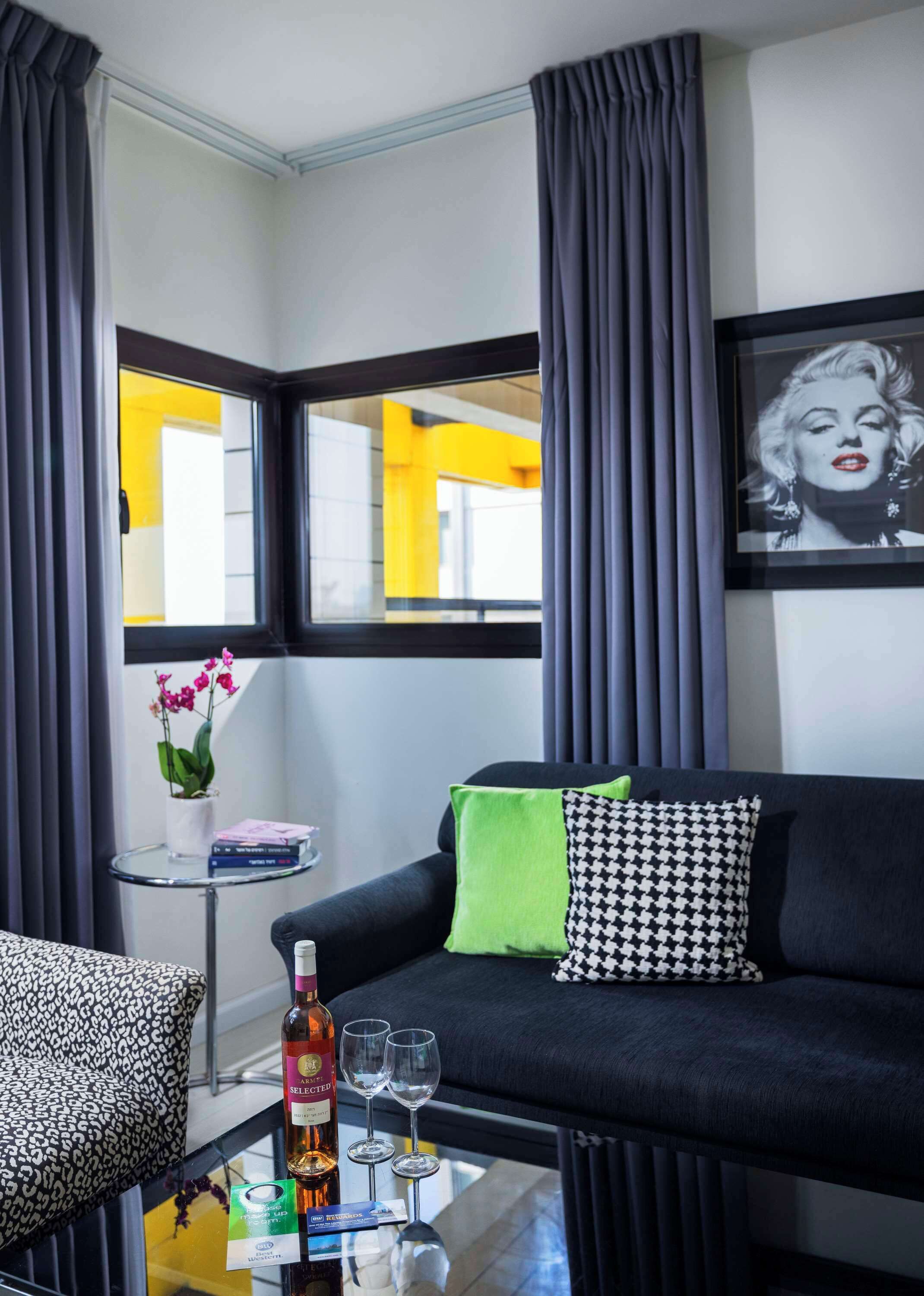 A modern living room with a black sofa, a glass coffee table, and a framed picture on the wall.