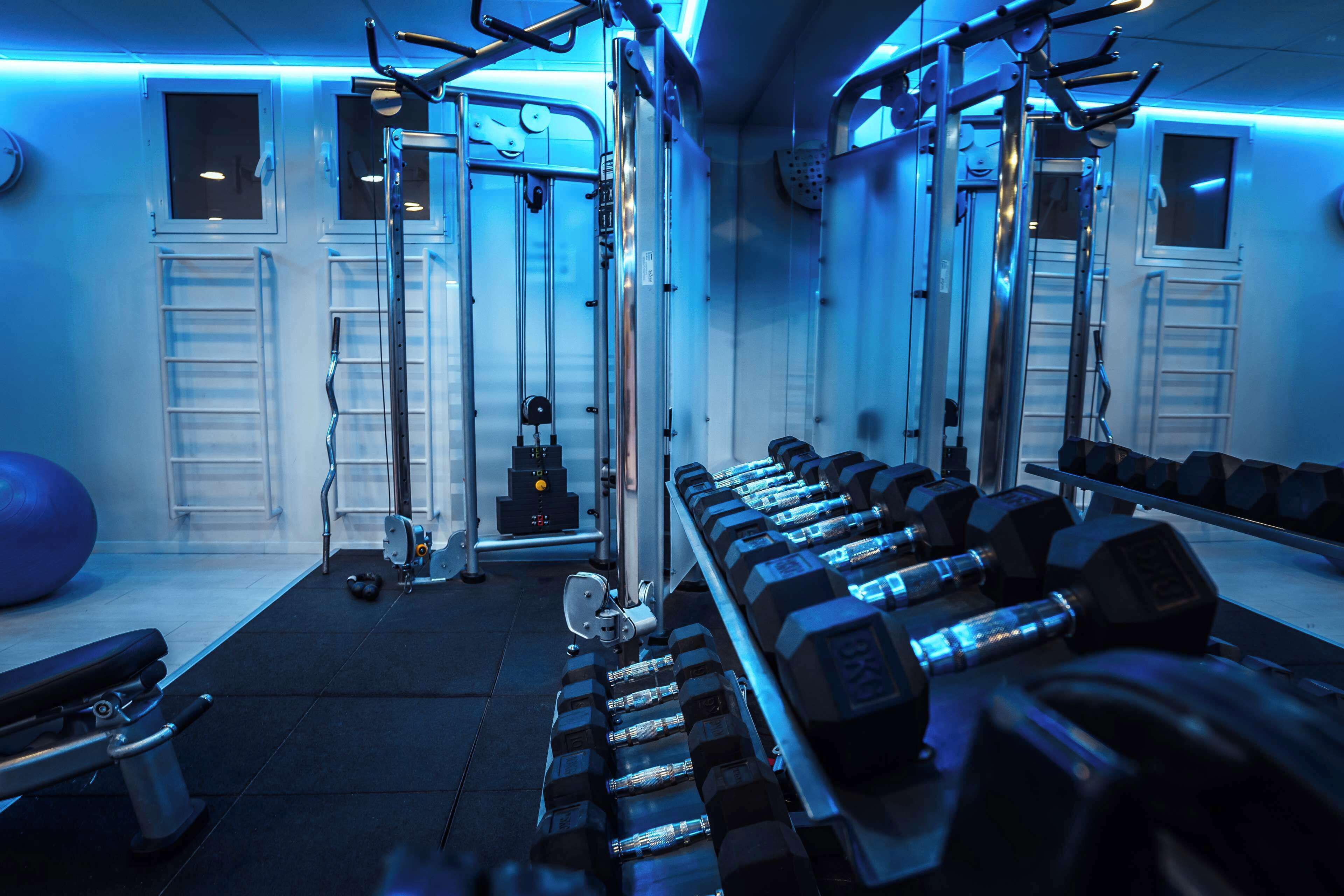 A gym with exercise equipment, benches, and dumbbells.