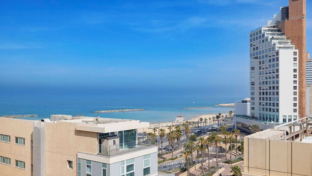 A coastal cityscape with modern buildings, a beach, and clear skies. - Best Western Regency Suites (Tel Aviv)