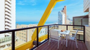 A balcony with a white table and chairs, overlooking a cityscape and the sea. - Best Western Regency Suites (Tel Aviv)