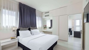 A modern hotel room with a large bed, bedside tables, a mirror, and a view of the adjacent living area. - Best Western Regency Suites (Tel Aviv)