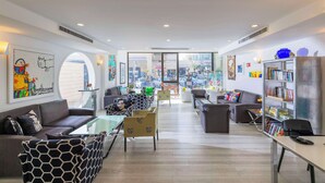 A modern living room with a sofa, armchairs, and a coffee table. There is a bookshelf filled with books and decorative items. - Best Western Regency Suites (Tel Aviv)