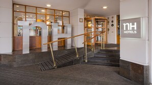 Un vestíbulo de hotel con una escalera, barandillas de madera y un mostrador de recepción.