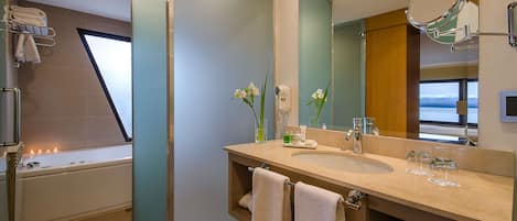 Un baño moderno con bañera, dos lavamanos, un espejo grande y un perchero para toallas.