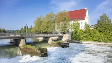 Un ponte sopra un fiume, con un edificio dal tetto rosso sullo sfondo.