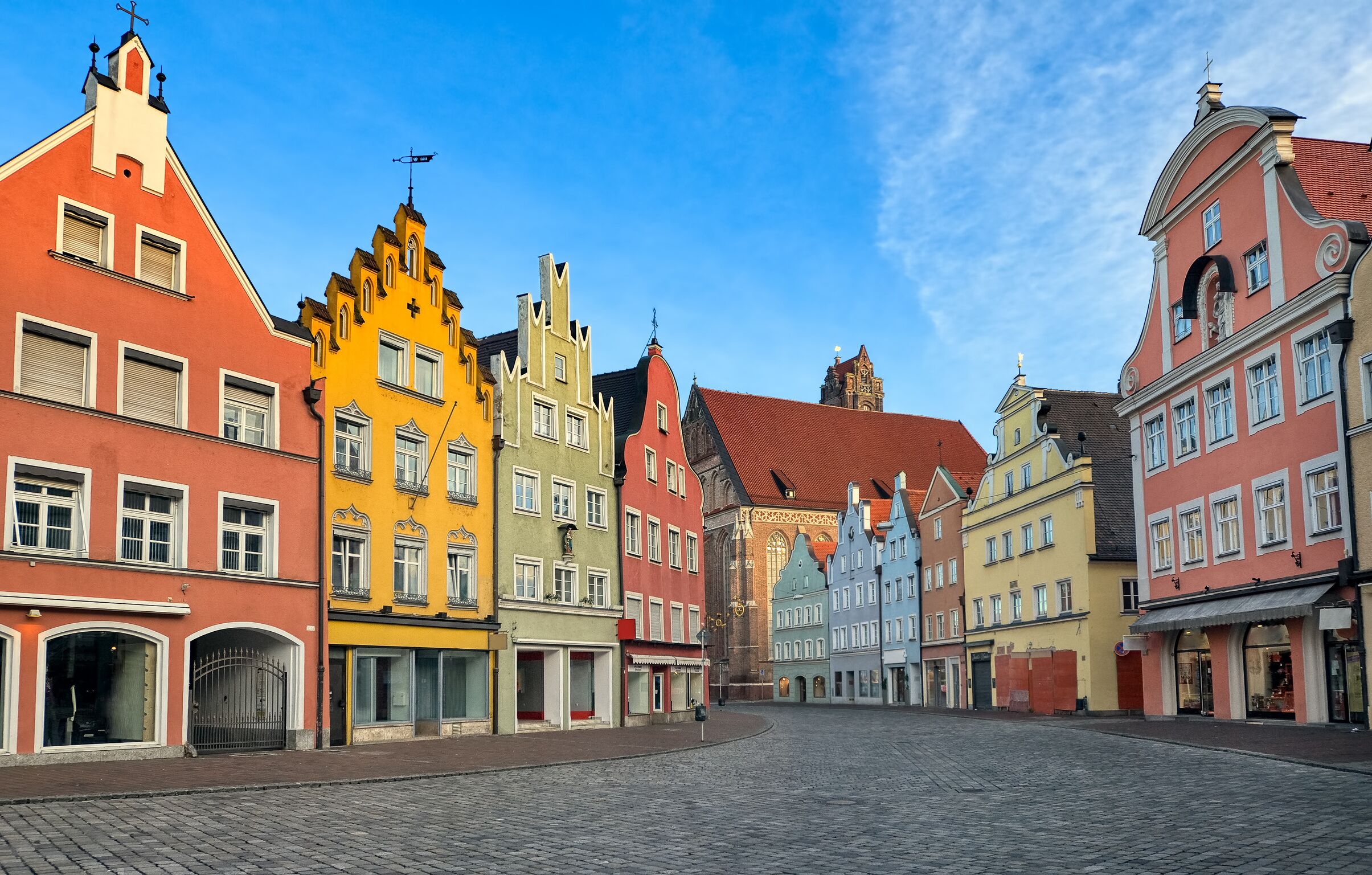 Eine Kopfsteinpflasterstraße gesäumt von bunten, historischen Gebäuden mit traditioneller Architektur und blauem Himmel.