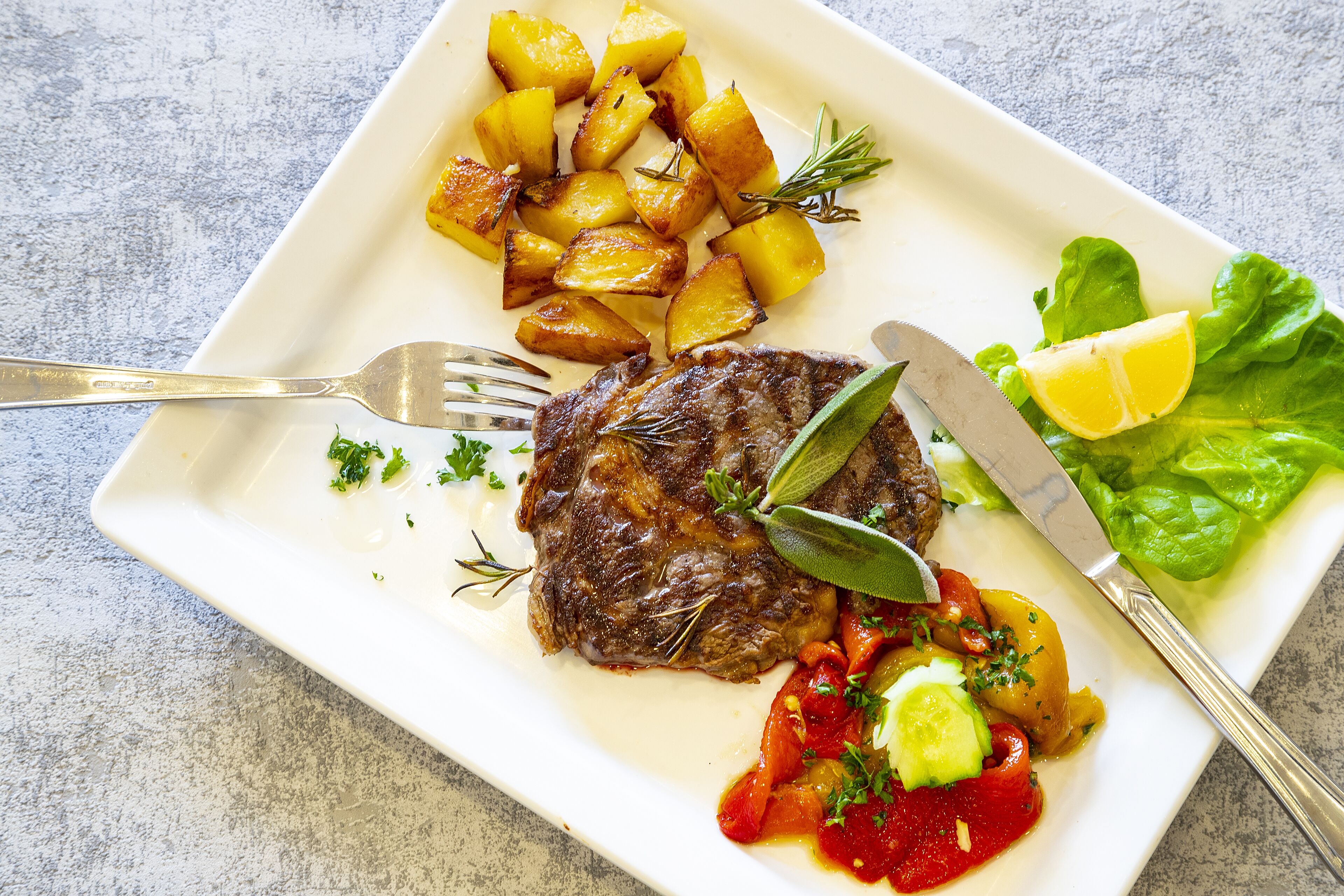Un plato con bistec, papas asadas y verduras.