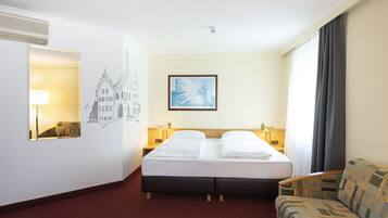 Una habitación de hotel con una cama, una silla, un cuadro y una lámpara.